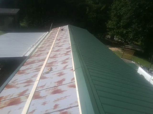 Old rusted panels beside newly installed green metal roofing — Wind Damage Roof Repair by Roofing Brothers in Lampasas