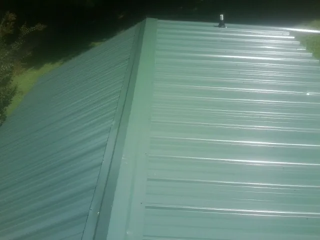 New green metal panels meeting at the ridge of a roof — Flat Roof Repair work by our crew in Lampasas