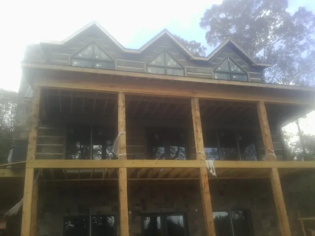 Dormers and porch framing on a large log home under construction — Roof Coating work by our crew in Lampasas