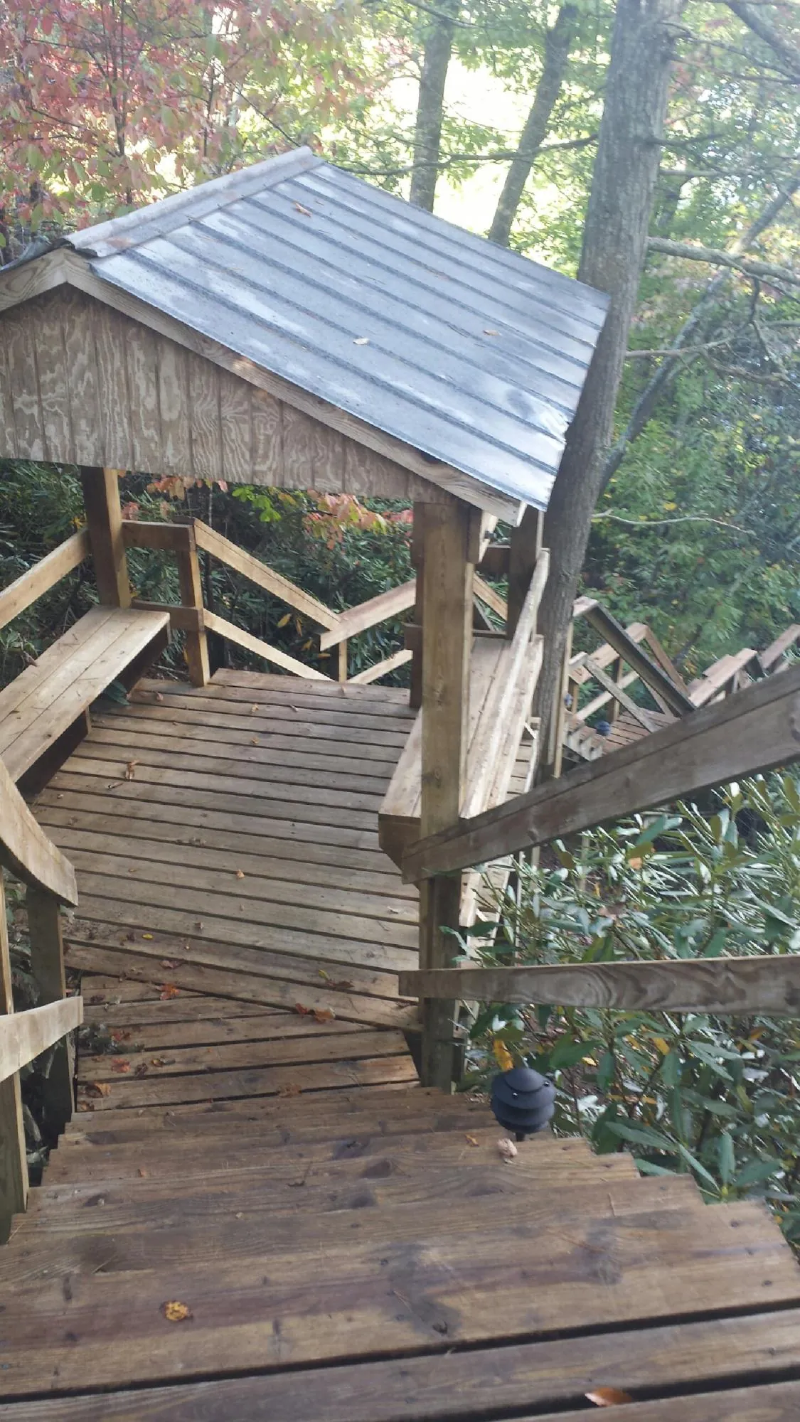 Metal roofed shelter over wooden steps on a wooded walkway — Skylight Repair & Installation work by our crew in Lampasas