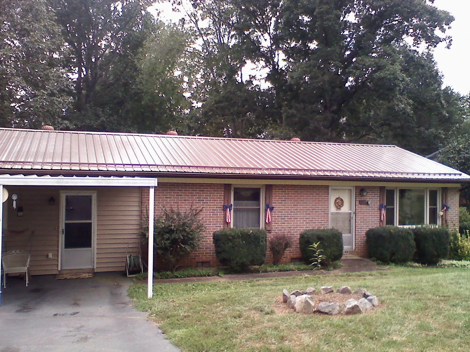 Bronze metal roof and carport on a brick ranch home — Roof Repair work by our crew in Lampasas
