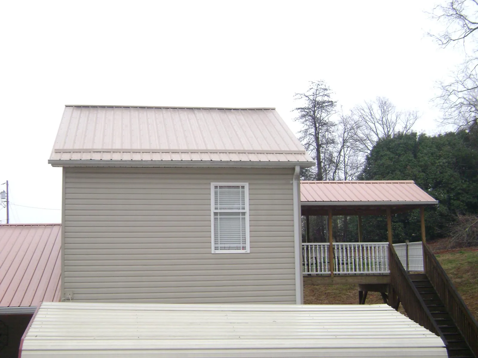 Tan metal roofs on a two story addition and attached porch, from a Roof Replacement job in Lampasas