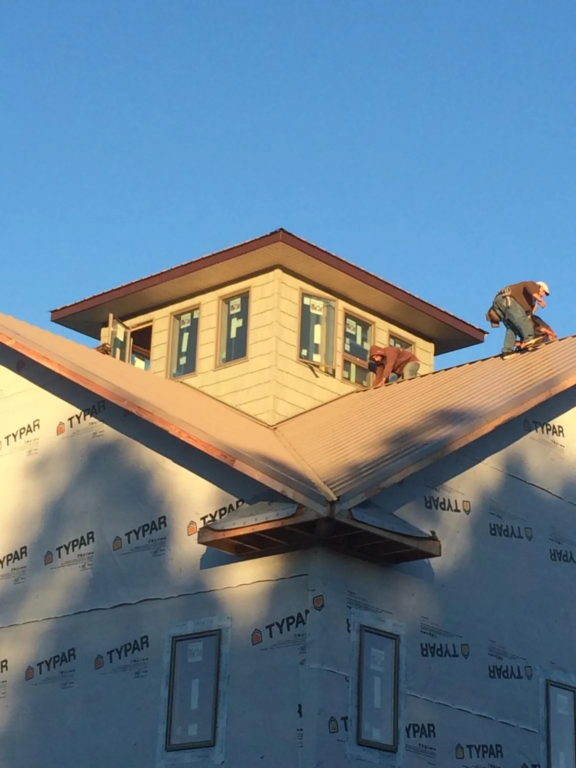 Roofers working around a rooftop cupola on a new metal roof at sunset — Roof Waterproofing in Lampasas by Roofing Brothers